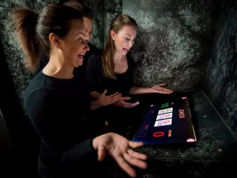 Joueuse concentrée sur une épreuve tactile dans une cellule